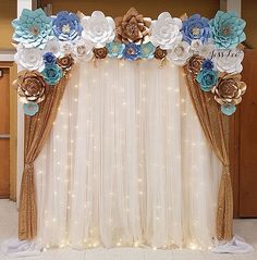 the backdrop is decorated with blue and white paper flowers, gold sequins and lights