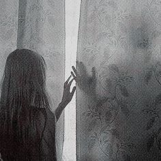 a woman standing in front of a window next to a curtain with her hands up