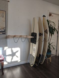 three surfboards are lined up against the wall in a room with wood floors and white walls