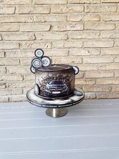 a cake sitting on top of a metal stand in front of a brick wall,