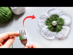 the crochet flower is being used to make a brooch with green yarn