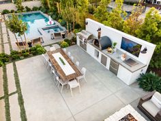 an aerial view of a backyard with a grill, table and seating area next to a swimming pool