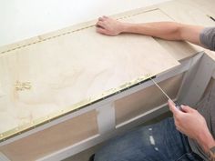 a man is working on a piece of plywood with a screwdriver in his hand