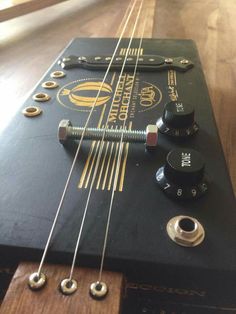 an electric guitar with several knobs and strings attached to the neck, sitting on a wooden floor