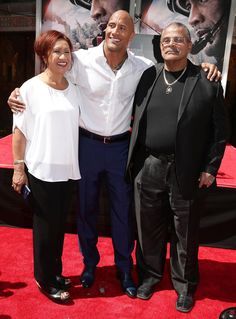 two men and a woman standing on a red carpet in front of a movie poster