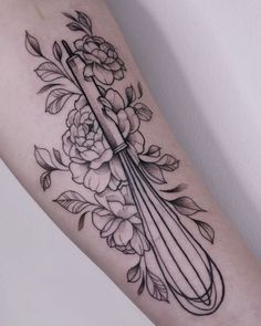 a woman's arm with flowers and a knife on it