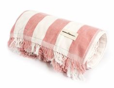 the pink and white striped blanket is folded on top of each other with fringes