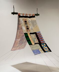 two pieces of art hanging from strings in the air, with one piece being folded over