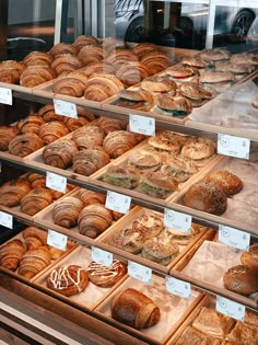 a display case filled with lots of different types of breads and pastries on wooden trays