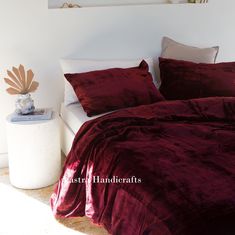 a bed with red sheets and pillows in a room next to a painting on the wall