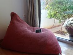 a red bean bag sitting on top of a hard wood floor next to a window