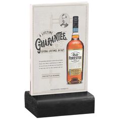 a bottle of whisky sitting on top of a wooden block next to a sign that says,