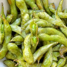 a white bowl filled with green beans on top of a table