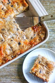 a casserole dish with meat and cheese in it next to a knife on a plate