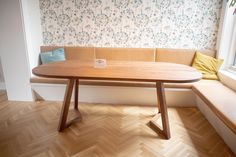 a wooden table sitting on top of a hard wood floor next to a white wall