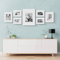 a white dresser sitting in front of a blue wall with pictures hanging on the wall