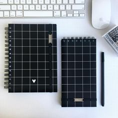 two notebooks sitting on top of a desk next to a computer keyboard and mouse