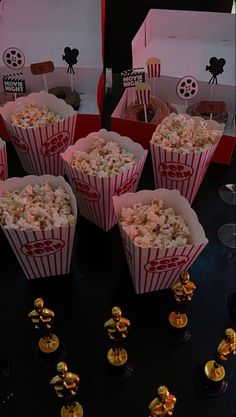 some popcorn is sitting in red boxes on a black table with gold decorations around it