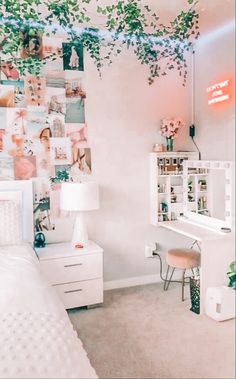 a bedroom with white furniture and lots of pictures on the wall above it, along with a plant hanging over the bed