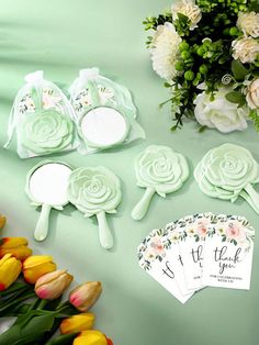 some flowers and paper tags on a green table next to yellow tulips with white roses