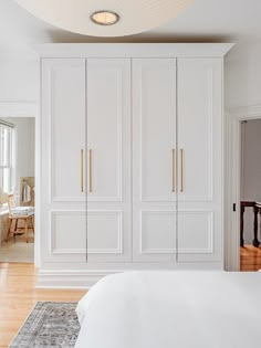 a bedroom with white furniture and wood flooring is pictured in this image, there are two lamps on the ceiling