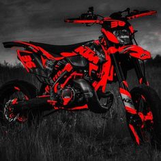 a red and black dirt bike parked in the grass