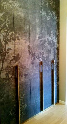 an empty room with wooden floors and blue wall paper on the walls, along with three metal doors