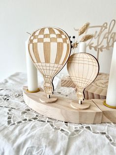 two wooden hot air balloons are on a table with candles and a lace doily