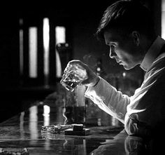 a man sitting at a bar with a glass in front of him and looking down