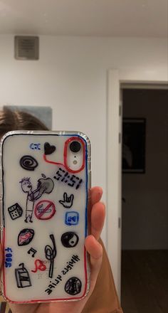 a person holding up a cell phone case with stickers on the back of it