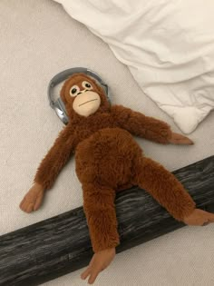 a stuffed monkey laying on top of a piece of wood with headphones attached to it