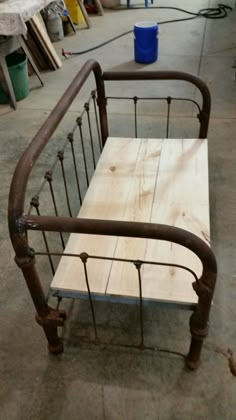 a wooden bench sitting on top of a metal bed frame in a room filled with tools