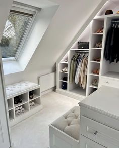 an attic bedroom with white closets and shelves filled with clothes, shoes and other items