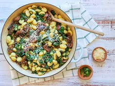 a skillet filled with pasta, mushrooms and spinach on top of a wooden table