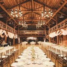 the tables are set for an event with white tablecloths on them and chandeliers hanging from the ceiling