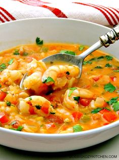 a bowl of shrimp and vegetable soup with a ladle in it, ready to be eaten