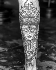 a person's leg with tattoos on it and an image of a buddha head