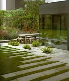 an empty bench in the middle of a garden with grass growing on it's sides