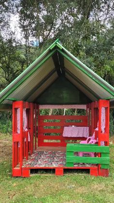 a red and green wooden shelter in the grass