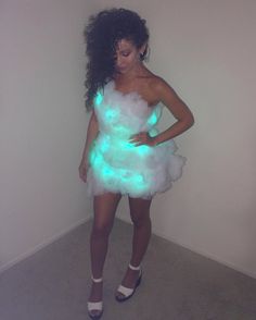 a woman in a white dress with green lights on her body and black hair is posing for the camera