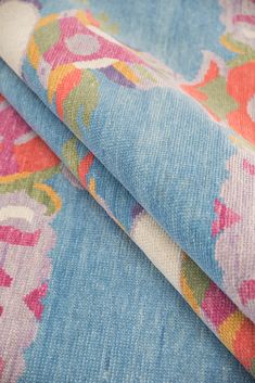 two pieces of blue and pink fabric with floral designs on the top one is rolled up