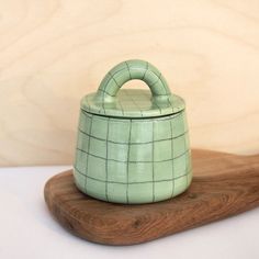 a small green pot sitting on top of a wooden board