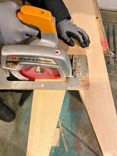 a person using a circular saw to cut plywood planks with a mitt