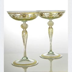 two glass goblets sitting next to each other on top of a white table