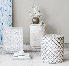 two white vases sitting on top of a table next to books and a painting