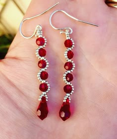 a pair of red glass beaded earrings on a person's hand