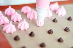 pink icing being spread over chocolate chips on a cookie sheet