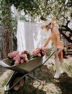 a woman pushing a wheelbarrow filled with flowers