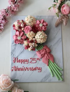 a happy 25th anniversary card with pink flowers and greenery on the table next to it