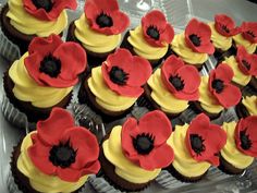 cupcakes with yellow frosting and red flowers in the shape of poppies